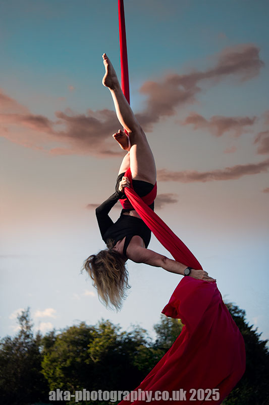 Aerial silk. Aerial performance outdoors on red silk.